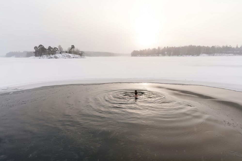 Winterliche Schneelandschaft mit einer Person, die in einem Eisbad schwimmt