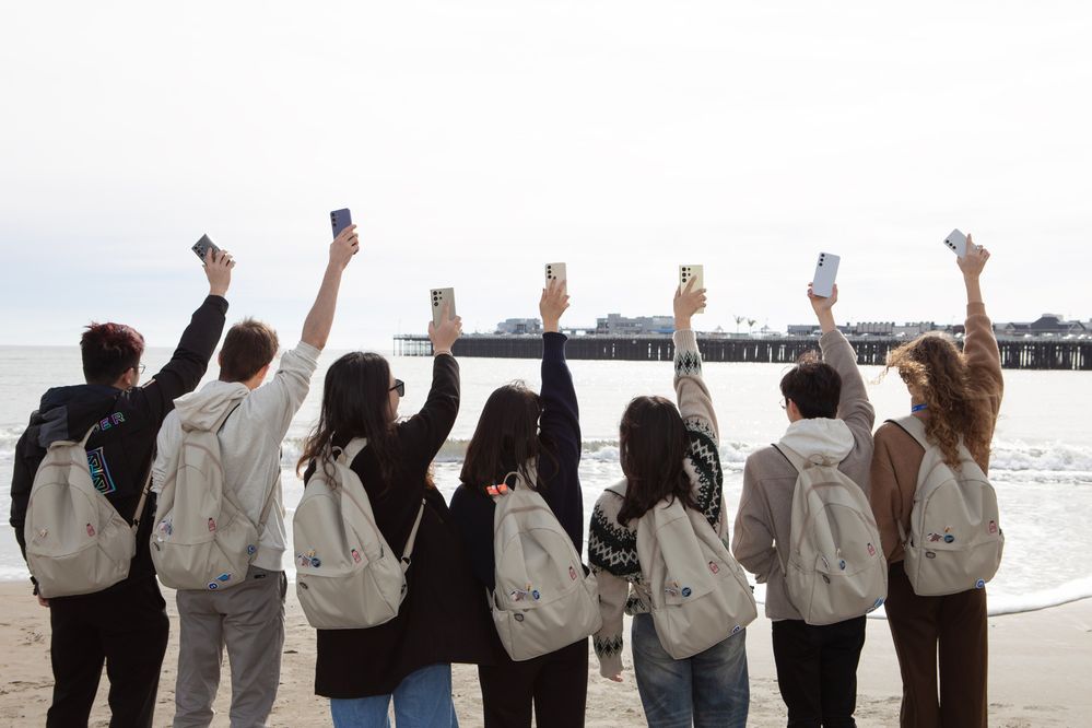Samsung Members Stars waving S24 Series devices in the hands at the beach.jpg